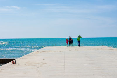 Rear view of men on beach against sky