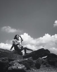 Woman standing on rock against sky