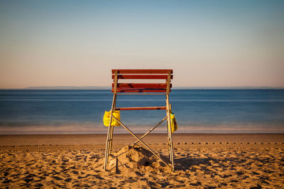 Empty lifeguard chair at beach against clear sky