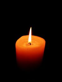 Close-up of lit candle in darkroom