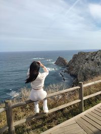 Rear view of woman standing by railing against sky