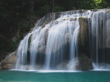 Scenic paradise waterfall with turquoise pond in rainforest. erawan falls, kanchanaburi, thailand.