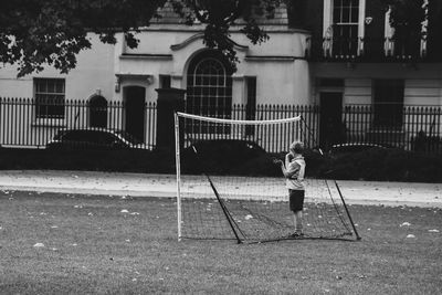 Full length of boy standing in city against building