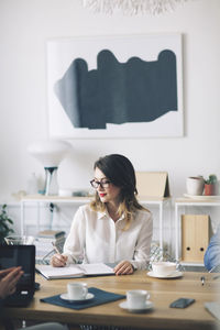 Young woman sitting on table at home