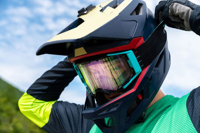 Guy adjusting motorcycle motocross helmet with goggles, close-up shot of relaxing while riding bike