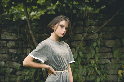 Portrait of a beautiful young woman standing against brick wall