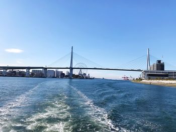 Bridge over calm sea against clear blue sky