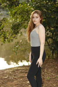 Portrait of beautiful woman standing by lake at park