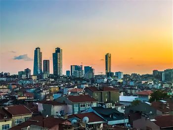 Buildings in city against romantic sky at sunset