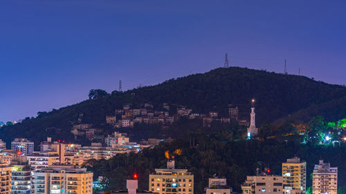 Illuminated buildings in city against clear sky at night