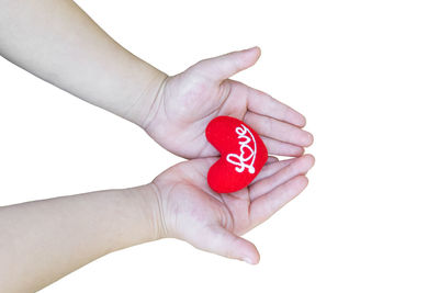Close-up of hand holding heart shape over white background