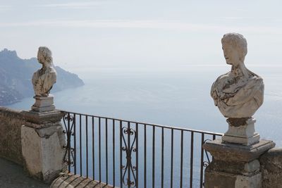 Statue by railing against sky