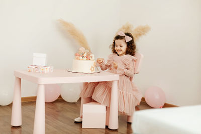 Happy little girl with a birthday cake at the table.