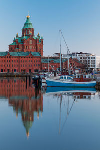 Boats moored at harbor with reflection of uspenski cathedral against sky