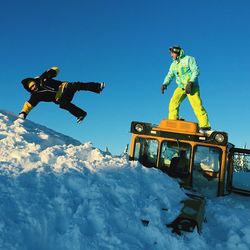Low angle view of men enjoying in snow against sky