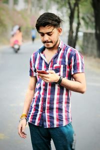 Young man looking away while standing on street