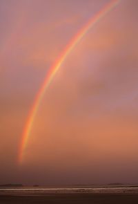 Scenic view of rainbow over sea against sky during sunset