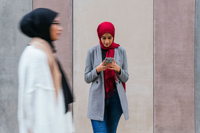 Arab female in hijab standing sending message on mobile phone and communication on social media standing on the street