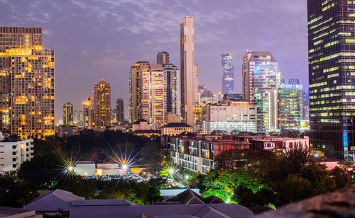 Illuminated buildings in city against sky