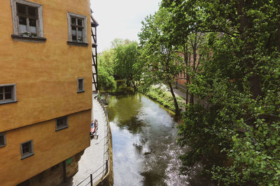 Canal amidst trees and buildings in city