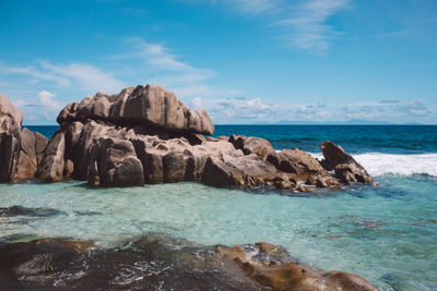 Rock formation on beach against sky