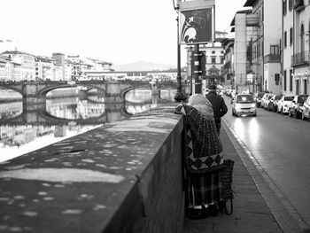 Rear view of man on bridge over canal in city