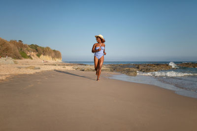 Full length of woman on beach against clear sky