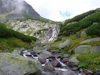 Scenic view of waterfall and mountains against sky