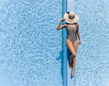 Young woman in bikini standing at swimming pool