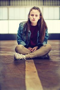 Portrait of a teenage girl sitting on wooden floor