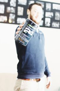 Midsection of man holding camera while standing against wall