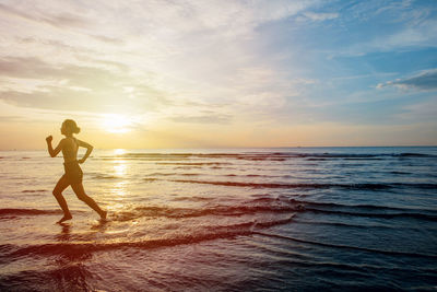 Full length of man on beach against sky during sunset