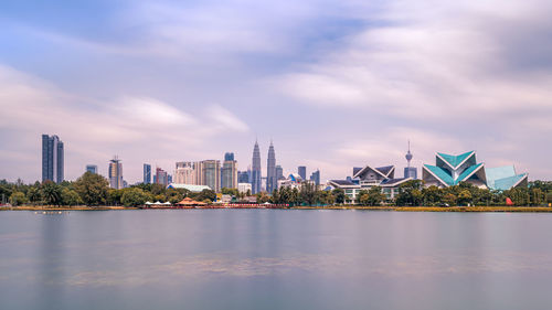 City at waterfront against cloudy sky