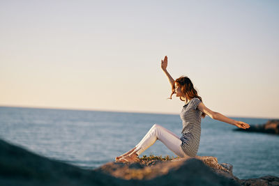 Midsection of woman at beach against sky during sunset