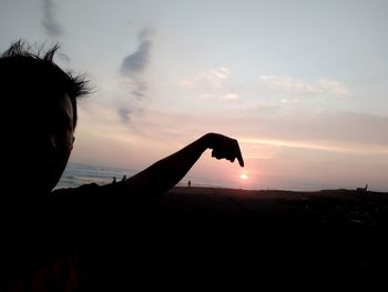 Portrait of silhouette man holding orange against sky during sunset