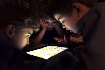 Siblings playing game on tablet computer at home