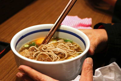 Close-up of hand holding soup in bowl