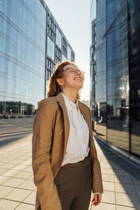 Smiling businesswoman with eyes closed standing on footpath