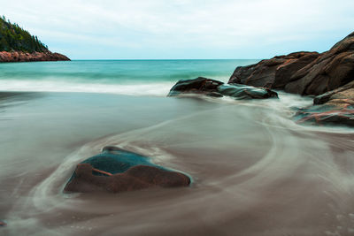 Surface level of rocks on beach against sky