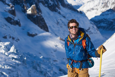 Smiling man in blue jacket stood still on a glacier