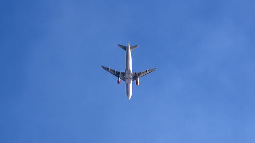 Low angle view of airplane against clear blue sky