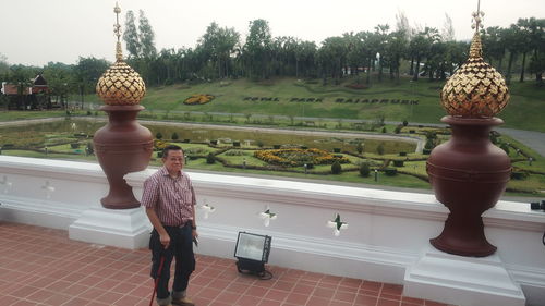 Man standing by statue against trees