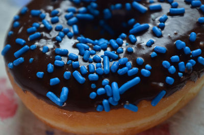 Close up of donut with chocolate icing and blue candy sprinkles