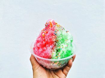 Person holding ice cream cone against white background