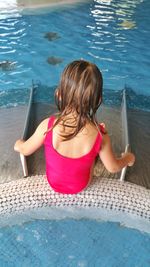 Rear view of girl sitting at poolside