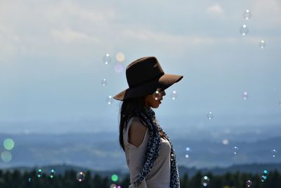 Woman with bubbles flying over sea against sky