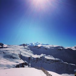 Scenic view of snowcapped mountain range against blue sky