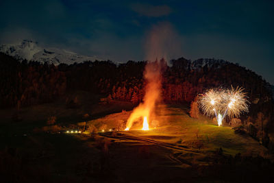 Firework display on field against sky at night