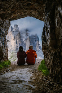 Rear view of people sitting on rock