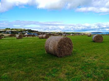 Hay bales on field against sky